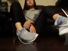 Chica asi&aacute;tica se quita los tenis y los calcetines